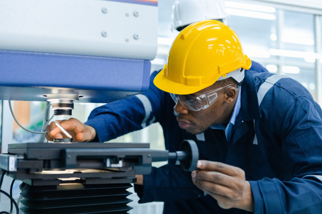 Specialist male African American engineer workers in manufacturing factory workplace. Microchip testing staff Operations of robots in industrial plants. Trade and research parts, modern production.